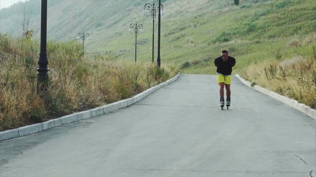 Young sporty man roller skating on summer park 4K
