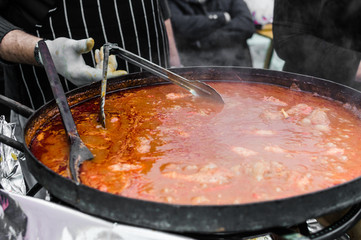 Cooking traditional Italian stew with sausages at a street food market