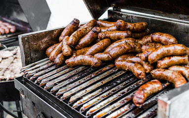 Argentina barbecue asado chorizo sausages cooking on parilla grill at a street food market