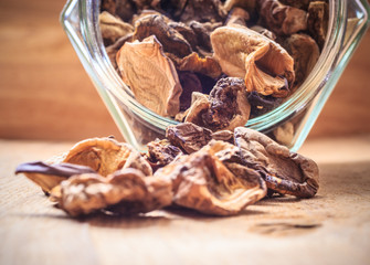Dry mushrooms in jar on wooden table.