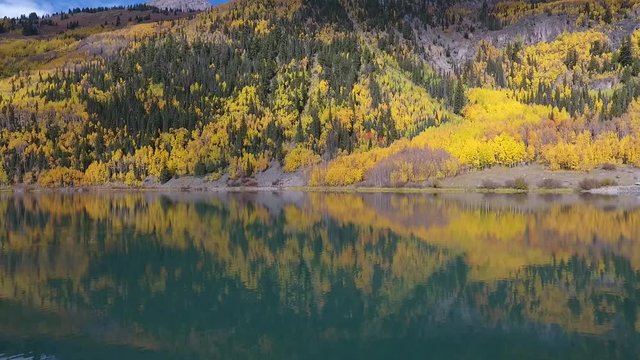 Aerial drone footage flying over a calm crystal clear lake in central Colorado