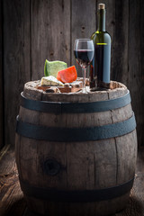 Wine in glass with mix of cheese on old barrel