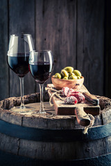 Tasty wine in glass with cold meats and olives on wooden board