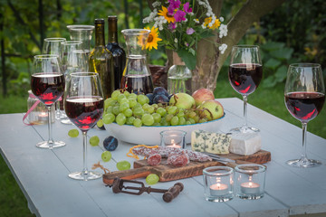 Beautiful table with wine and candles in garden at dusk