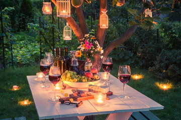 Beautiful table full of cheese and meats in garden at dusk