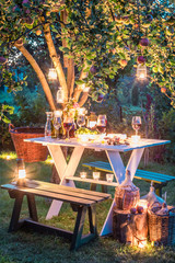 Fototapeta premium Gorgeous table full of wine and fruits in garden at dusk