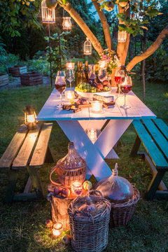 Gorgeous Table With Wine And Candles In Garden At Dusk