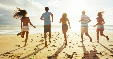 Group of friends having fun running down the beach at sunset - Powered by Adobe