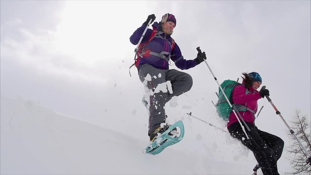 Two friends leap of a snowy ledge having fun.