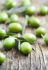 Fresh green olives with leaves on wooden background