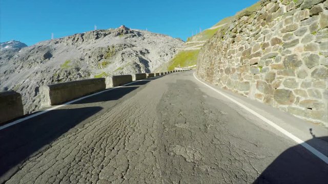 Driving through hairpin turns of Stelvio Pass, highest pass in the Alps on sunny summer day