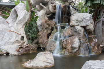 Fototapeta na wymiar Waterfall motion on a stone in the garden. Beautiful nature 