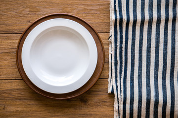 white plate and fork on old wooden table with checked tablecloth