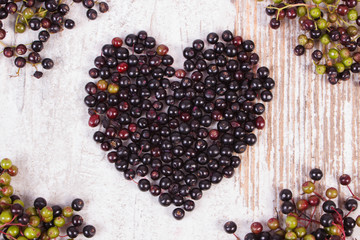 Heart of fresh elderberry on old wooden background, symbol of love