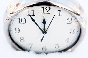 Metallic old watch in snow.