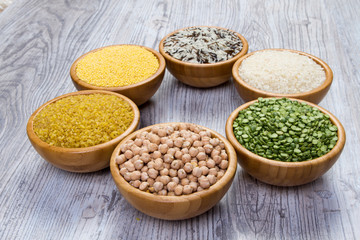 Set of cereals, peas, rice, millet, chickpeas sprinkled in bamboo bowls on wooden background