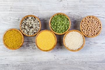 Set of cereals, peas, rice, millet, chickpeas sprinkled in bamboo bowls on wooden background