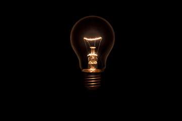 Tungsten light bulb without wiring and socket on black background. Concept for creative idea.