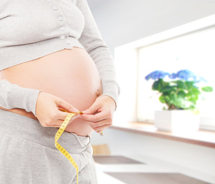 Pregnant belly of a young woman in a beautiful interior