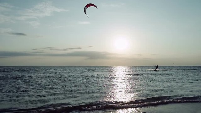 Kitesurfing. Silhouettes of two surfers riding on boards on the surface of waves at sunset. Azov sea. HD