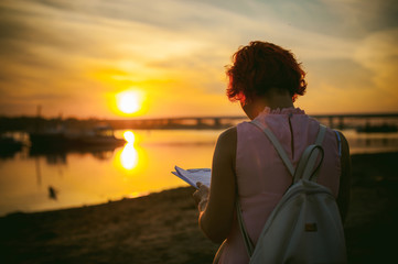 woman with dyed red hair in a pale pink dress with white backpack, signed important documents...