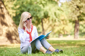 Working outside. Full lenght portrait of beautiful smiling businesswoman making call while sitting outdoor in coffee break.