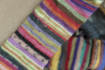 Striped colorful woolen knitted fabric closeup on brown cardboard. Blurred background.
