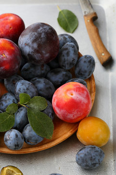 Ripe plums on wood plate closeup