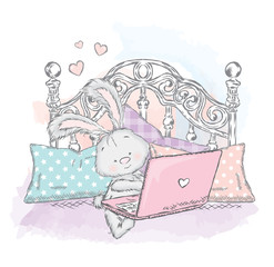 Cute hare in bed with laptop. Bunny the pillows. Vector illustration for a card or poster. Figure for printed products. Design.
