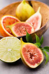 Mixed citrus fruit figs, limes on a gray background.