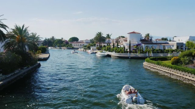 Steadicam shot: channel with the elite real estate. Empuriabrava, Spain, Catalonia. Floats small boat with tourists