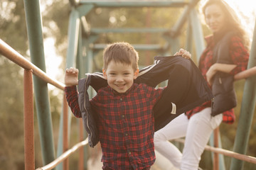 Mother with son sitting on a bridge in sunny day