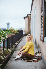 girl sitting on the balcony at the window. autumn, view of the city