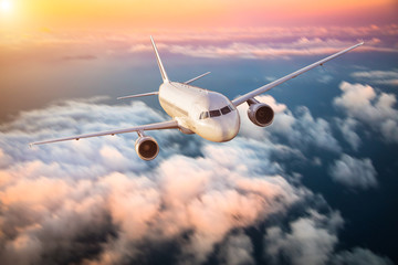 Fototapeta premium Samolot latający nad chmury w dramatyczny zachód słońca