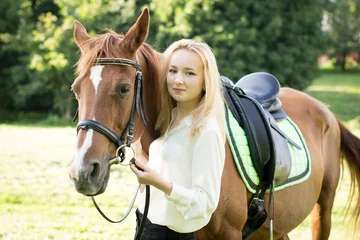 Foto op Canvas Молодая девушка со светлыми волосами стоит рядом с коричневой лошадью  © natasidorova 