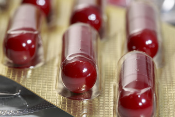 Close-up of expired hard-shelled gelatin red capsules into golden bundle
