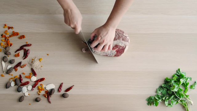 Top View of Chefs Hands Cutting Beaf. Raw Meat Slices Chopped On Wooden Board.