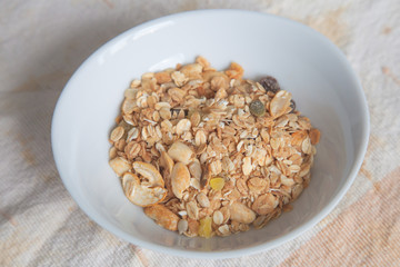 Muesli in white bowl; natural breakfast and snack food closeup.