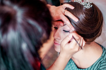Fototapeta premium Beautiful young bride with wedding makeup and hairstyle in bedroom, newlywed woman final preparation for wedding. Happy Bride waiting groom. Marriage Wedding day moment. Bride portrait soft focus