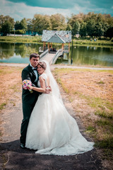 Bride and groom walking on the river, smiling, kissing. 
