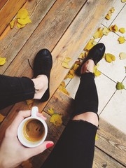 Drinking coffee sit outside cafe, terrace, gold autumn with yellow leafs at the street