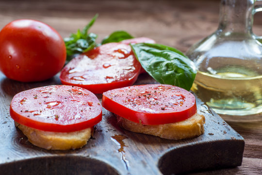 Toasts with soft cheese and cherry tomatoes over wood background