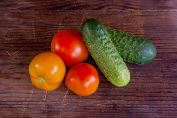 Close up view of fresh, ripe tomatoes and cucumbers on wood back