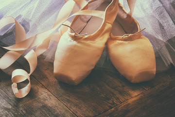 Image of silk pointe shoes and tutu on wooden floor. Vintage filtered

 - obrazy, fototapety, plakaty