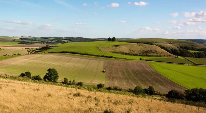 Farmer sowing seeds on field in Wiltshire, England. Tractor planting crops in field, in front of Middle Hill in the Imber Range, in the British autumn