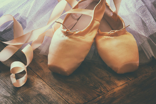 Image of silk pointe shoes and tutu on wooden floor. Vintage filtered


