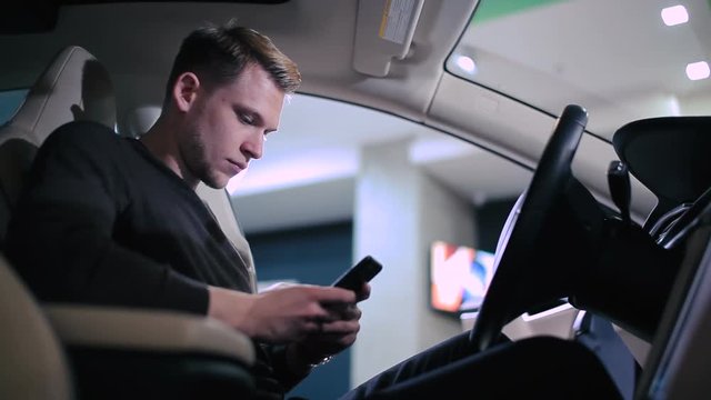 Man looking at the smartphone inside the car