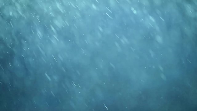 Artistic falling raindrops on soft blue background.