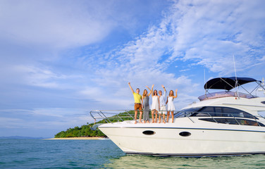 Friendship and vacation. Happy young people standing on the yacht deck and enjoying the view,...