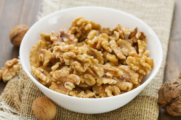 walnut in white bowl on brown wooden background